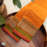 Devi Consecrated Cotton Saree – Golden Orange with Olive Green & Rust Red Traditional Floral Border
